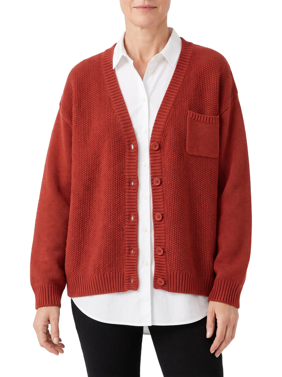 Women's oversized red knit pocket cardigan worn open over a white shirt