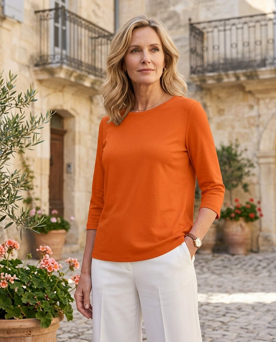 Woman in her early 50s wearing an orange crew neck three-quarter sleeve top